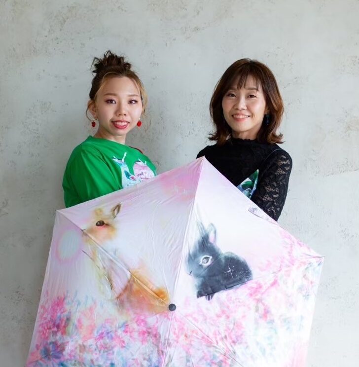 ネウネウと井原ちよが作品の傘を持つ写真